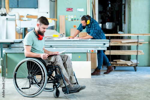 worker in wheelchair in a carpenter's workshop with his colleagu