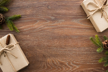 Christmas composition background on wood table with gift boxes and pine branches with cones. Top view with copy space, flat lay.