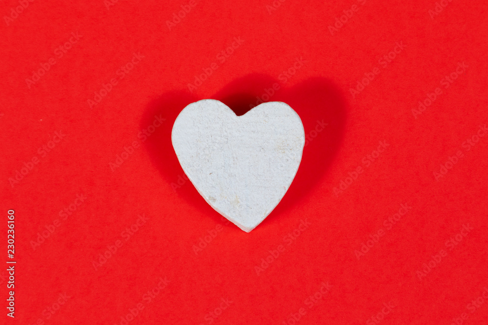 White wooden heart on red background White wooden heart on red background
