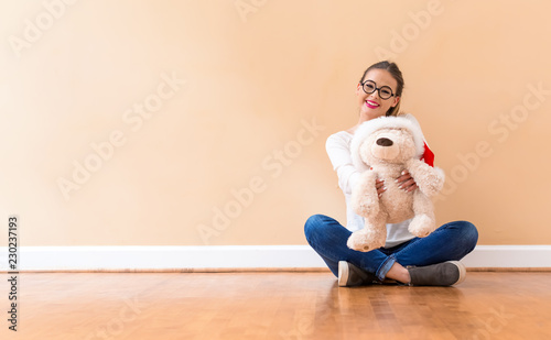 Young woman holding a teddy bear against a big interior wall
