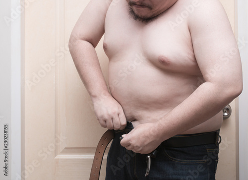 Overweight man trying to fasten too small jean pants. Represent of fat,  obesity, big belly. Stock Photo