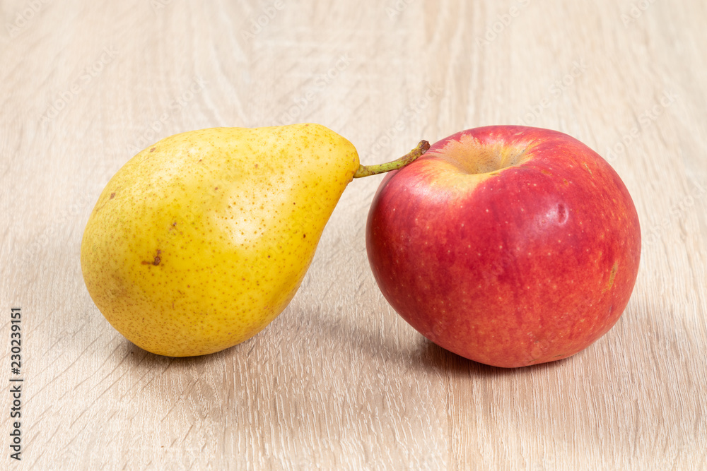 Ripe pear and apple beside eatch other on wooden table Ripe pear and apple beside eatch other on wooden table