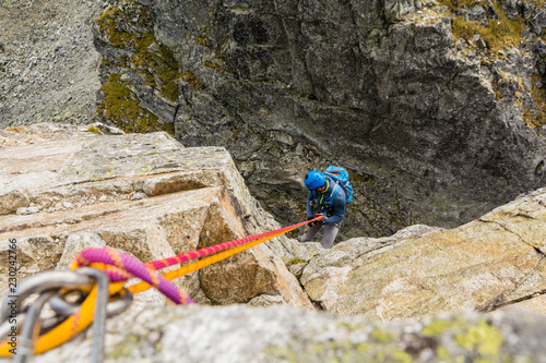 The climber overcomes a vertical fault with a rope.