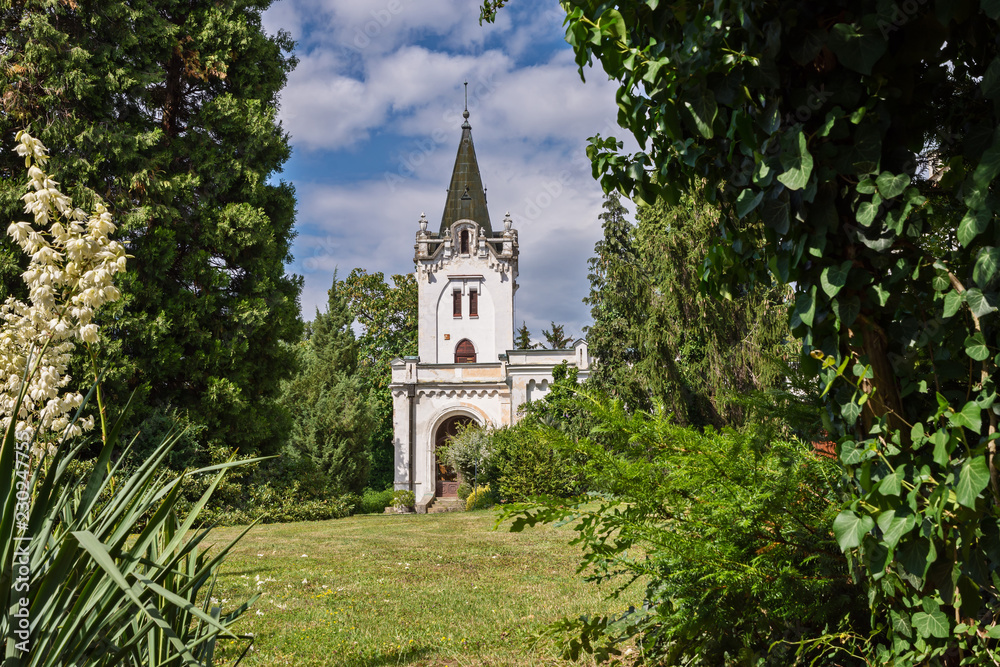 chapel with bell tower among the trees in the park and blue sky