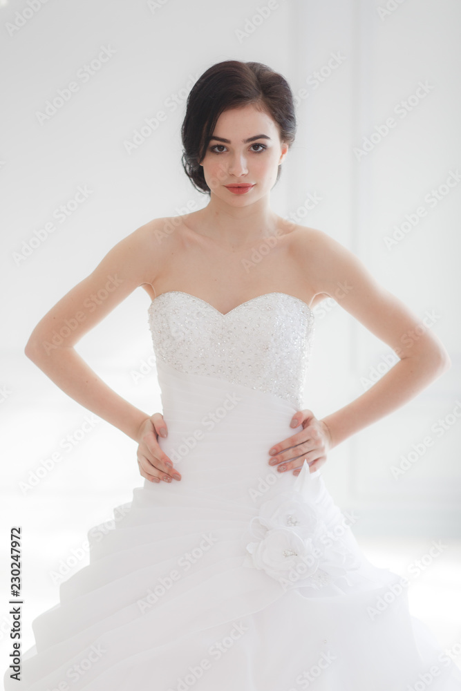 The beautiful young woman posing in a wedding dress over grey background studio room The beautiful young woman posing in a wedding dress over grey background studio room