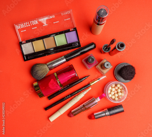 The composition of accessories, makeup cosmetics on a bright red background. Top view. 