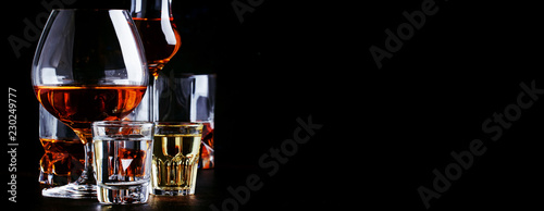 Set of strong alcoholic drinks in glasses and shot glass in assortent: vodka, rum, cognac, tequila, brandy and whiskey. Dark vintage background, selective focus