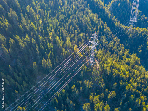 Aerial view of power line pylon in mountaineous area in Switzerland through valley in Canton of Valais