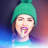 Cool teenage girl with colorful candy and hat, wearing modern makeup. Closeup, retouched, studio lighting.