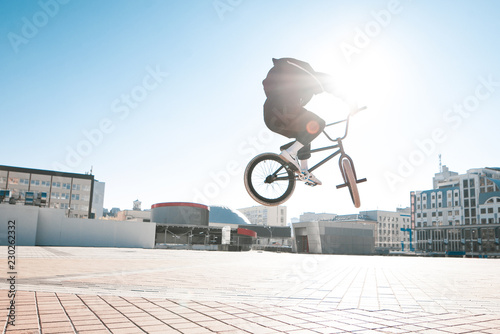 BMX freestyle. BMX cyclist makes complex tricks on a bike. Young man makes spectacular stunts against the background of the city square.