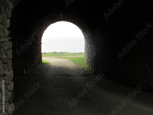View of the ocean through a stone archway on a foggy day 