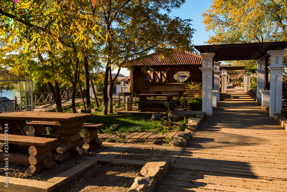 Autumn view of riverside park with wooden houses and benches