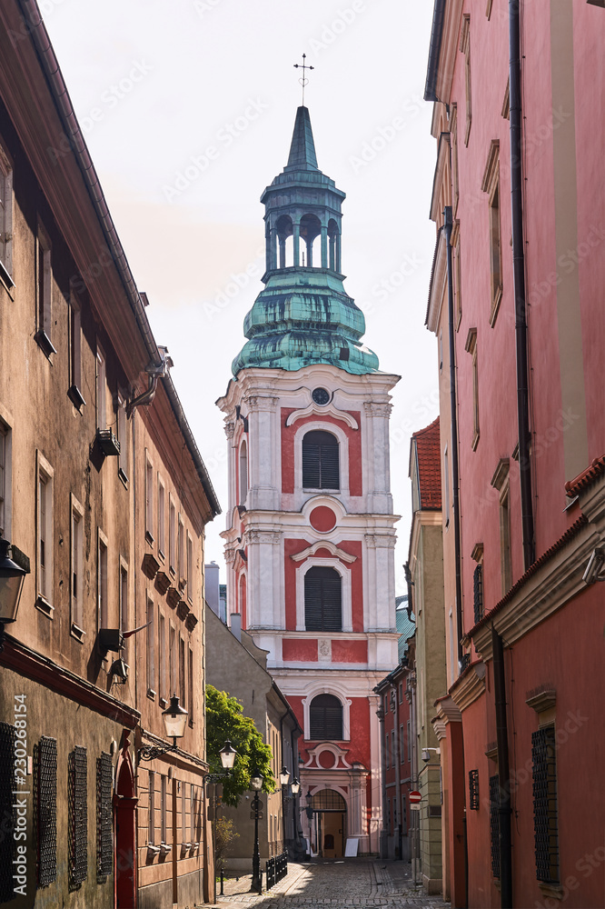 Baroque monastery tower and a cobbled street in Poznan.