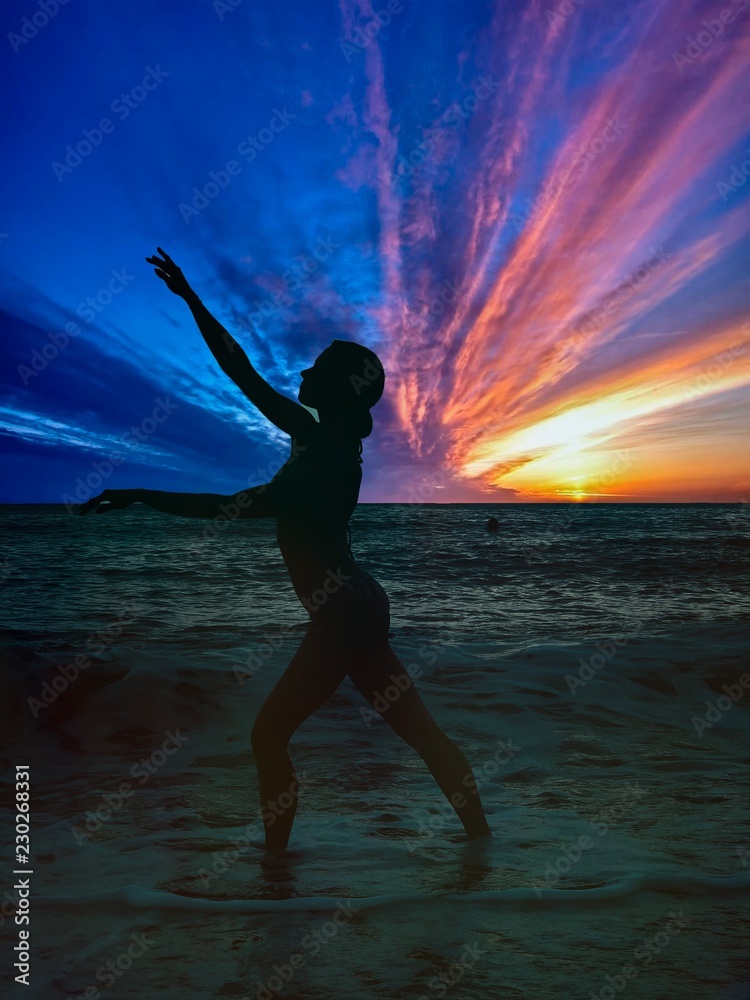 silhouette of young woman on the beach at sunset