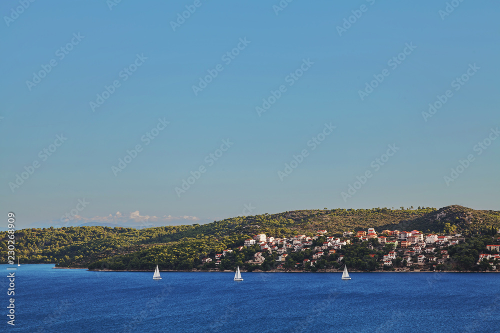 Three boats sailing in front of a small beautiful city built on an island in the sea Three boats sailing in front of a small beautiful city built on an island in the sea
