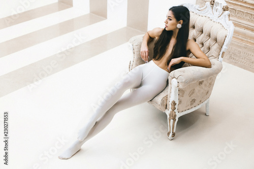 Young elegant girl in white pantyhose sits in luxurious chair