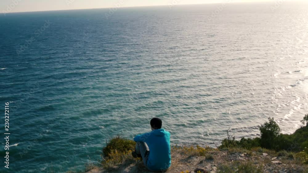 man sits on a mountain and looks at the sea man sits on a mountain and looks at the sea