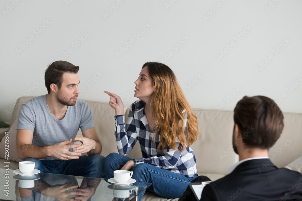 Annoyed nervous wife accusing, blaming husband. Young couple, family at meeting with psychologist counselor doctor. Mental problems in family, distrust, emotional discussion of breaking up Annoyed nervous wife accusing, blaming husband. Young couple, family at meeting with psychologist counselor doctor. Mental problems in family, distrust, emotional discussion of breaking up