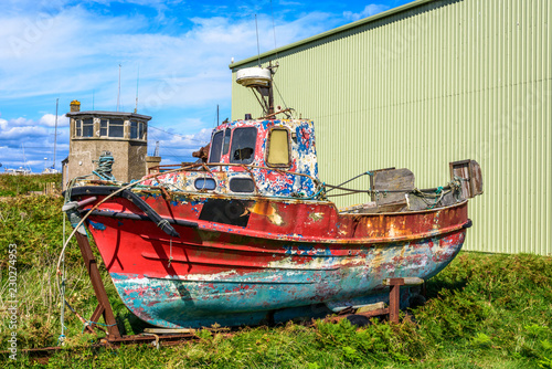 Colorful rusty boat in front of a factory hall, Ireland