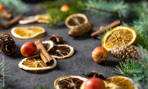 Sliced dried orange with christmas pine branches on dark texture surface. Holiday background.
