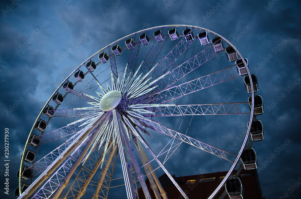Big luminous ferris wheel in front of dark blue dramatic sky