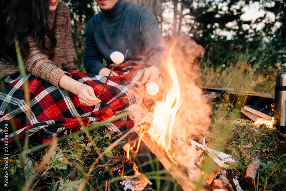 Fototapeta premium Summer Camp Fire. Tourism sexy photo. Cute couple kissing in the park on a sunny day. Adventure concept. Man and woman kissing. Couple in love. Camping fire. Love story. Romance lovers. Fashion photo.
