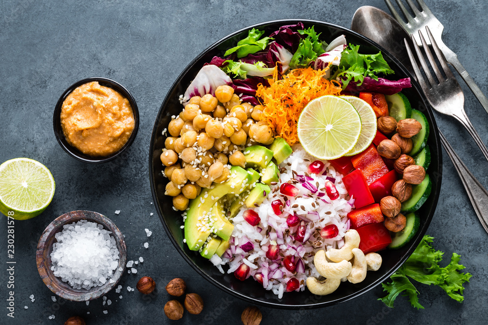 Healthy vegetarian Buddha bowl with fresh vegetable salad, rice, chickpea, avocado, sweet pepper, cucumber, carrot, pomegranate and nuts closeup - obrazy, fototapety, plakaty 
