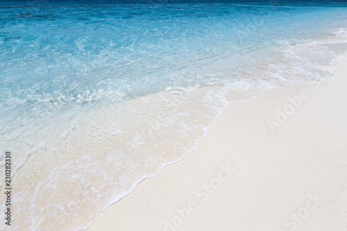 Azure clear sea on sandy beach with foam wave, copy space