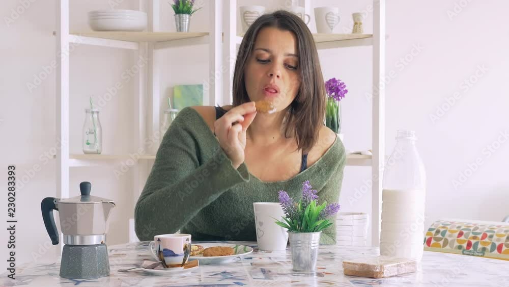 Beautiful woman having breakfast at home in the morning with biscuit milk and coffee Beautiful woman having breakfast at home in the morning with biscuit milk and coffee