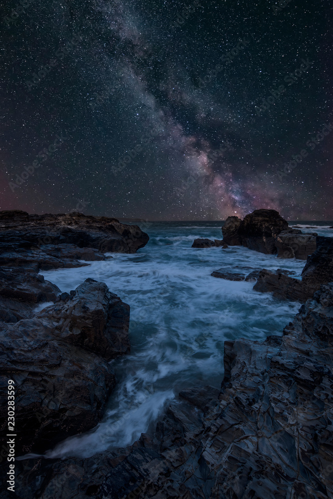 Vibrant Milky Way composite image over landscape of Cornwall coastline in England