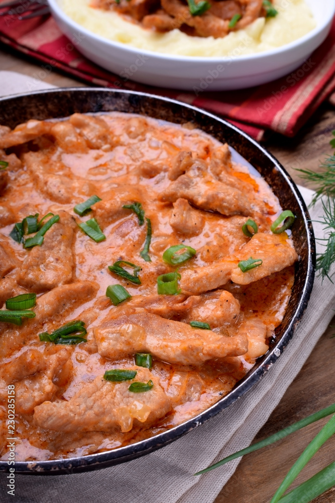 Pieces of meat stewed in tomato and sour cream sauce in the frying pan Pieces of meat stewed in tomato and sour cream sauce in the frying pan