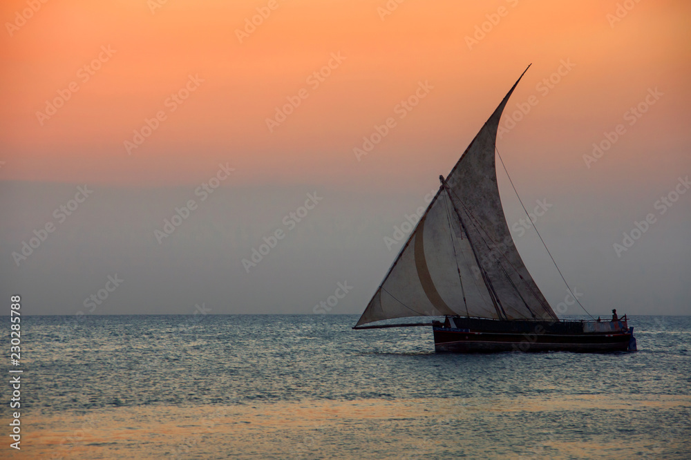 Traditional dhow boat with sailor at sunset, Zanzibar, Tanzania