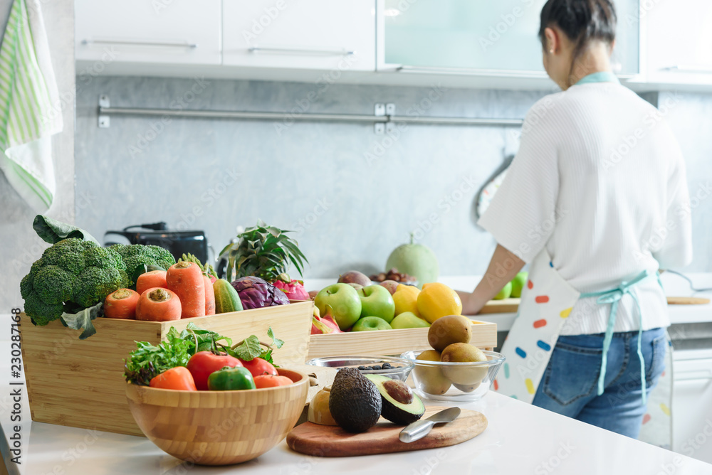Woman in kitchen with various kind of vegetable and fruits that all are good for health and no meat, vegan lifestyle Woman in kitchen with various kind of vegetable and fruits that all are good for health and no meat, vegan lifestyle