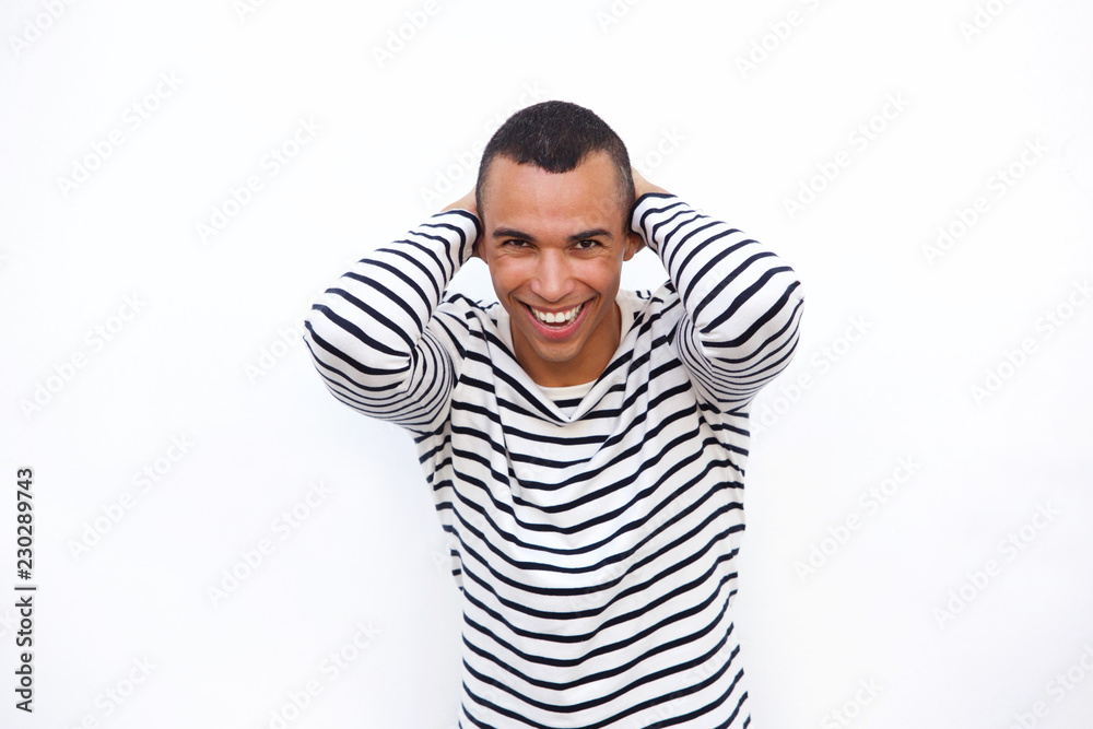 happy young man laughing with hands behind head against isolated white background happy young man laughing with hands behind head against isolated white background