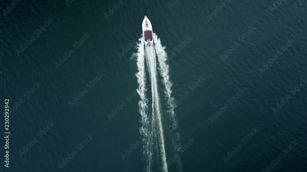 Top down tracking shot of a bigger speed boat cruising on water
