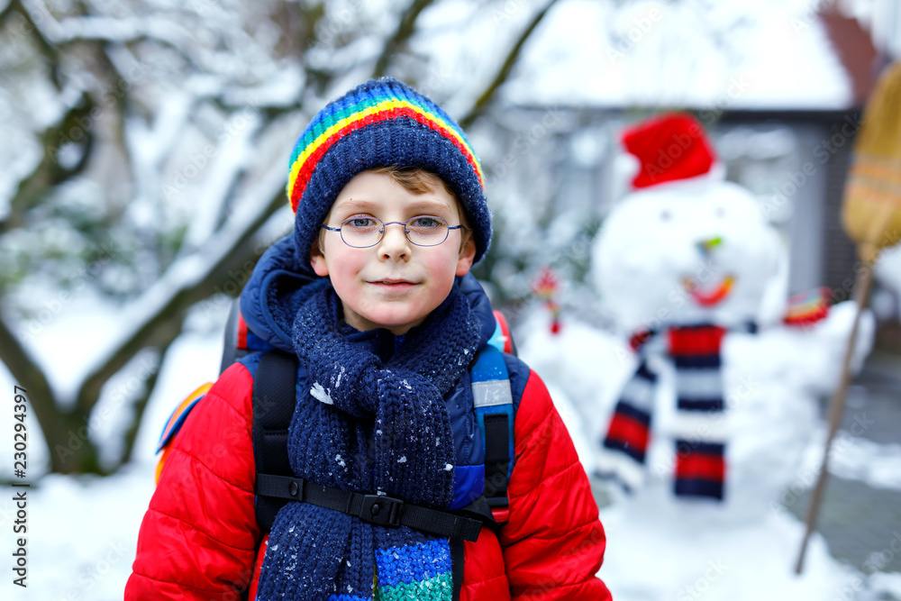 Happy kid boy with glasses having fun with snow on way to school, elementary class Happy kid boy with glasses having fun with snow on way to school, elementary class
