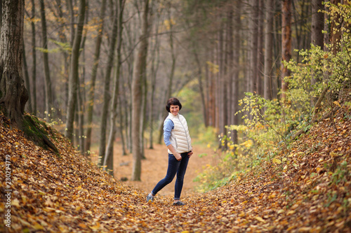 Girl in a yellow autumn forest. Beautiful young woman walks along the path of the autumn forest. 
