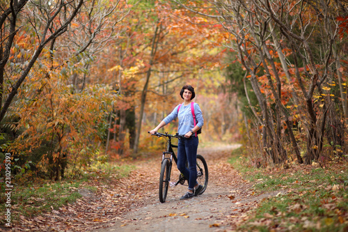 The girl on a bike in the forest. Beautiful young woman posing for the camera in the autumn forest.
