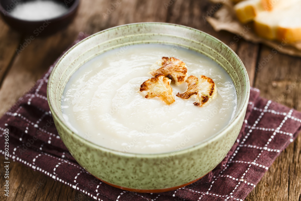 Fresh homemade cream of cauliflower soup garnished with roasted cauliflower floret slices (Selective Focus, Focus in the middle of the right floret on the soup) Fresh homemade cream of cauliflower soup garnished with roasted cauliflower floret slices (Selective Focus, Focus in the middle of the right floret on the soup)