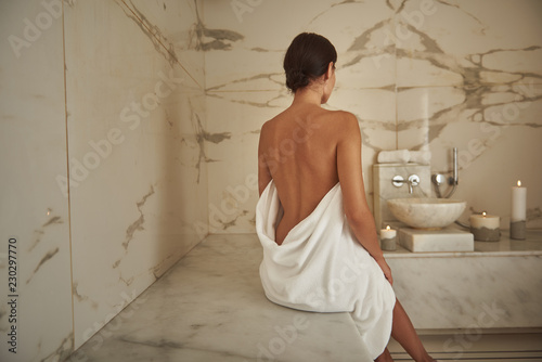 Clean skin. Calm dark haired woman showing her beautiful back while sitting in the hammam alone