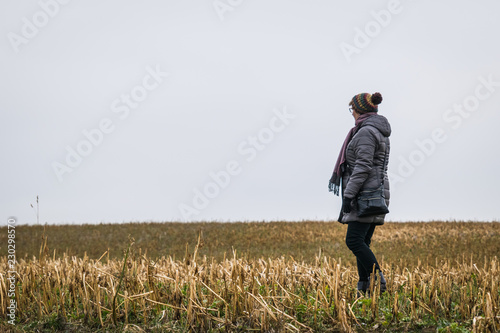 Frau steht auf einem Feld und guckt in die Ferne