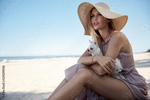Portrait of an elegant woman relaxing on a beach with her beloved pet