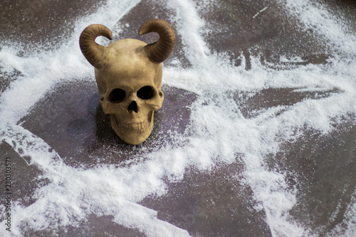 Close-up on man`s skull with horns on satan`s pentacle on floor