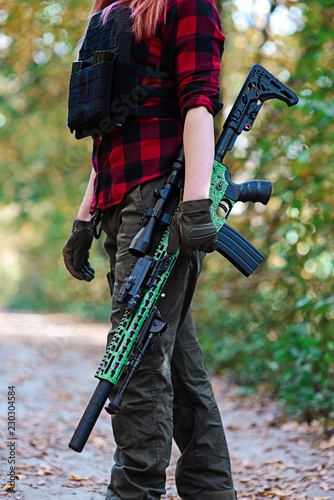 Sniper rifle in female hands.Selective focus/Sniper rifle with telescopic sight and silencer in the hands of girl against the background of the forest