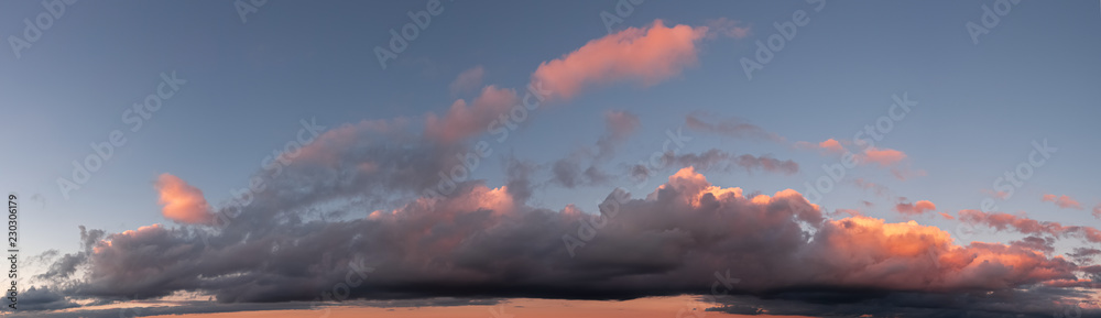 Panoramic photo of blue sky and dramatic clouds at sunset. Sunset light on the clouds. Panoramic photo of blue sky and dramatic clouds at sunset. Sunset light on the clouds.