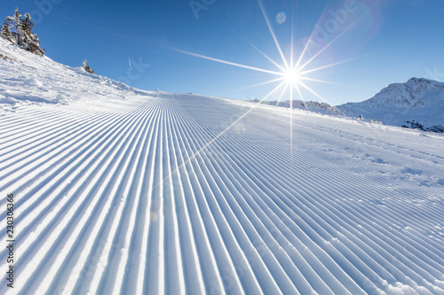 Fresh snow on ski slope during sunny day.