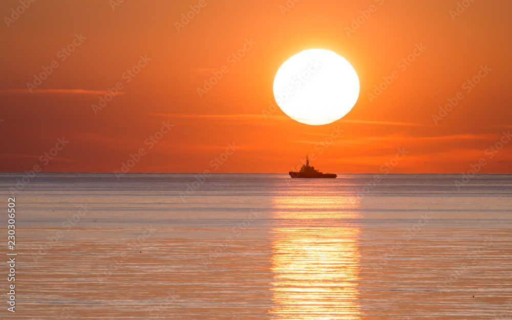 Guard ship silhouette on the background of big low sun. Sunset on Baltic sea. Guard ship silhouette on the background of big low sun. Sunset on Baltic sea.