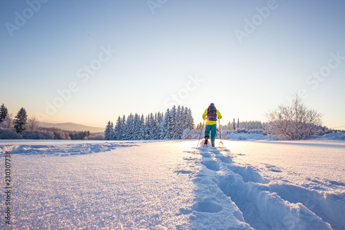 Snowshoe walker running in powder snow with beautiful sunrise light. photo