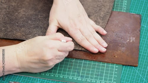 craftsman punches edge of leather for handbag by stitching punch and hammer photo