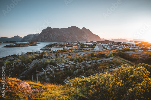 Sunrise and Sunset at Henningsvaer, fishing village located on several small islands in the Lofoten archipelago, Norway over a blue sky with clouds.
